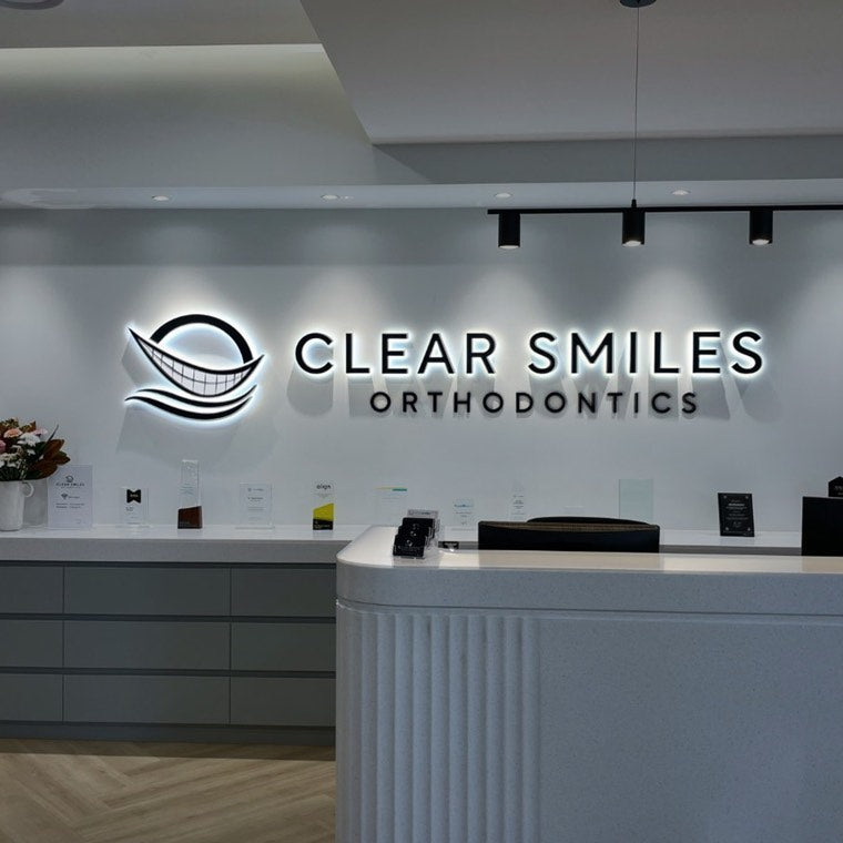 Dental clinic reception sign illuminated above a waiting bench