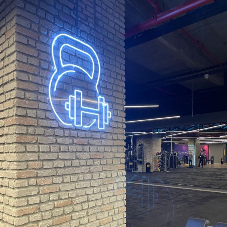 Neon dumbbell and flex mark inside a fitness studio