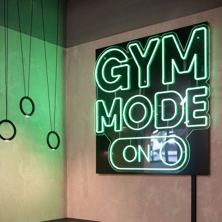 Bold illuminated logo wall inside a boutique gym entry